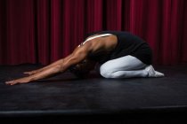 Балерино выполняет упражнения на растяжку на сцене — стоковое фото