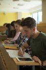 Giovani studenti universitari che studiano alla scrivania in classe — Foto stock