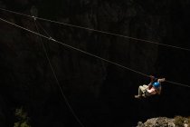 Vue latérale à angle élevé de la femme caucasienne profitant du temps dans la nature, tyrolienne par une journée ensoleillée dans les montagnes. Fun week-end aventure vacances. — Photo de stock