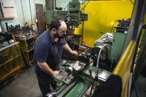 Trabalhador da fábrica masculino caucasiano em uma oficina fazendo equipamentos hidráulicos, usando óculos de segurança, operando máquinas. — Fotografia de Stock