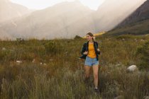 Frontansicht einer kaukasischen Frau, die an einem sonnigen Tag eine gute Zeit auf einem Ausflug in die Berge hat, auf einem Feld spazieren geht — Stockfoto