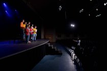 Вид збоку на багатоетнічну групу підлітків-чоловіків і жінок, що тримають ноти і співають на сцені шкільного театру під час репетицій для виступу — стокове фото
