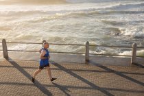 Высокий угол обзора взрослого кавказца, тренирующегося на набережной в солнечный день, бегущего — стоковое фото