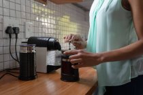 Vue latérale section médiane de la femme à la maison, debout dans la cuisine préparant le café dans un café — Photo de stock