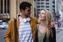 Vista frontal de perto de um casal caucasiano feliz nas ruas da cidade durante o dia, abraçando e sorrindo . — Fotografia de Stock