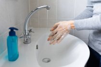 Fermer la section médiane de la femme portant un pull gris, se lavant les mains avec du savon liquide. Distance sociale et isolement personnel en quarantaine. — Photo de stock