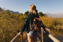 Rear view close up of a Caucasian woman having a good time on a trip to the mountains, standing on a bridge, enjoying her view, on a sunny day — Stock Photo