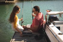 Um homem caucasiano e sua filha adolescente segurando varas de pesca e falando — Fotografia de Stock