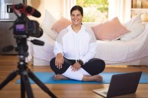 Caucasian female vlogger at home in her sitting room, demonstrating exercises for her online blog recording with a camera. Social distancing and self isolation in quarantine lockdown. — Stock Photo