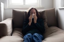 A Caucasian woman spending time at home, blowing her nose. Lifestyle at home isolating, social distancing in quarantine lockdown during coronavirus covid 19 pandemic. — Stock Photo