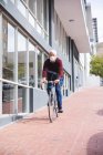 Senior Caucasian man out and about in the city streets during the day, wearing a face mask against coronavirus, covid 19, riding his bicycle. — Stock Photo