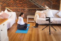Femme vlogger caucasienne à la maison dans son salon, démontrant des exercices pour son blog en ligne enregistrement avec une caméra. Distance sociale et isolement personnel en quarantaine. — Photo de stock