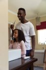 Menina afro-americana e seu pai se distanciam socialmente em casa durante o confinamento de quarentena, passando um tempo juntos, escovando os dentes em um banheiro . — Fotografia de Stock