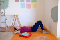 Caucasian woman spending time at home self isolating and social distancing in quarantine lockdown during coronavirus covid 19 epidemic, taking a break while renovating her home, lying on the floor. — Stock Photo