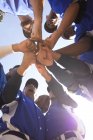 Vue en angle bas d'une équipe multiethnique de joueurs de baseball masculins, se préparant avant un match, se motivant mutuellement dans un câlin faisant une pile de main par une journée ensoleillée — Photo de stock