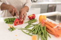 Close up mid section of African American woman spending time at home, social distancing and self isolation in quarantine lockdown during coronavirus covid 19 epidemic, chopping vegetables on a chopping board — Stock Photo