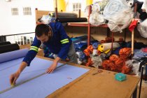 Ein kaukasischer Arbeiter in einer Werkstatt in einer Fabrik, die Rollstühle herstellt, steht an einer Werkbank, benutzt ein Metalllineal und markiert Material — Stockfoto