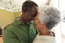 Großaufnahme eines glücklichen älteren afroamerikanischen Rentnerehepaares zu Hause, das in seiner Küche steht, die Köpfe aneinander berührt, einander anschaut und lächelt, während er sich umarmt, zu Hause zusammen isoliert während der Coronavirus-Covid19 Pandemie — Stockfoto