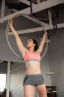 Front view of a fit attractive Caucasian woman enjoying pole dance training at a studio, hanging on a hoop, holding it with both hands — Stock Photo