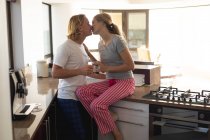 Caucasian couple sitting in a kitchen, drinking coffee, embracing and kissing. Social distancing and self isolation in quarantine lockdown. — Stock Photo