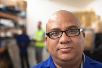 Портрет змішаної раси чоловіка-працівника в окулярах на складі на заводі, що робить інвалідні візки, дивлячись на камеру — стокове фото