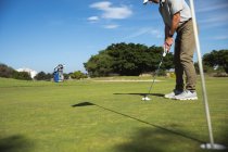У сонячний день з блакитним небом на поле для гольфу вимальовується кавказький чоловік, який вдаряється в м 
