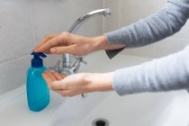 Nahaufnahme einer Frau in grauem Pullover, die sich vor dem Waschen Flüssigseife über die Hände gießt. Soziale Distanzierung und Selbstisolierung in Quarantäne. — Stockfoto