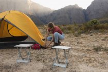 Vista lateral de uma mulher caucasiana se divertindo em uma viagem às montanhas, montando uma tenda — Fotografia de Stock