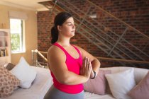 Vlogger femminile caucasica a casa nel suo salotto, dimostrando esercizio di yoga per il suo blog online. Distanziamento sociale e autoisolamento in quarantena. — Foto stock
