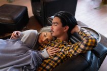 Frontansicht eines jungen Mannes mit gemischter Rasse und einer jungen kaukasischen Frau, die die Zeit zu Hause genießt, sich in ihrem Wohnzimmer ausruht, auf der Couch liegt, sich im Schlaf umarmt. — Stockfoto