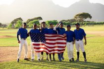 Jugadores de béisbol en línea con una bandera americana - foto de stock