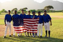 Jugadores de béisbol en línea con una bandera americana - foto de stock