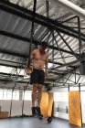 Передній вид на безсоромного атлета Кавказького чоловіка перехресне тренування в спортзалі, штовхає себе на гімнастичні кільця, піднімаючи вагу тіла — стокове фото