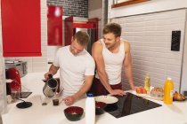 Vista frontale della coppia maschile caucasica rilassarsi a casa, in piedi in cucina, preparare la colazione insieme — Foto stock