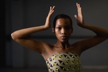 Портрет змішаної раси жіночої танцівниці в жовтій сукні, танцює в студії своїми руками вгору . — стокове фото
