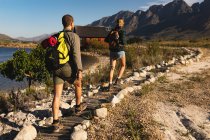 Погляд ззаду нагадує пару з Кавказу, яка добре проводить час, подорожуючи горами, йдучи по стежці, в сонячний день. — стокове фото