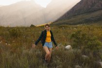 Vista frontal de uma mulher caucasiana se divertindo em uma viagem às montanhas, andando em um campo, em um dia ensolarado — Fotografia de Stock