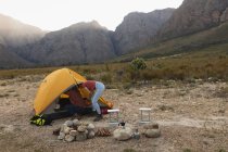Seitenansicht eines kaukasischen Paares, das sich bei einem Ausflug in die Berge amüsiert und ein Zelt aufstellt — Stockfoto