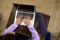 Overhead-Ansicht eines jugendlichen kaukasischen Mädchens in einem Klassenzimmer, das am Schreibtisch sitzt, sich konzentriert und einen Laptop benutzt — Stockfoto