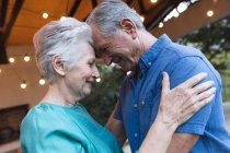 Side view of a happy retired senior Caucasian couple at home, touching heads together and looking at each other while embracing, at home together isolating during coronavirus covid19 pandemic — Stock Photo