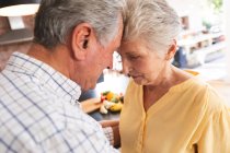 Close up of happy retired senior Caucasian couple at home holding hands, dancing together, touching heads in their kitchen and smiling, at home together isolating during coronavirus covid19 pandemic — Stock Photo