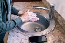 Close up of woman at home in bathroom during daytime washing her hands in a sink, using soap, protection against coronavirus Covid-19 infection and pandemic. Social distancing and self isolation in quarantine lockdown — Stock Photo