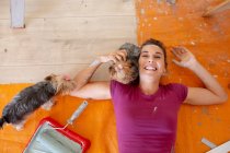 Femme en détresse sociale peignant les murs de sa maison avec ses chiens — Photo de stock