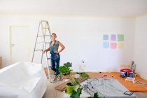 Caucasian woman wearing blue jeans dungarees, spending time at home self isolating and social distancing in quarantine lockdown during coronavirus covid 19 epidemic, taking a break while renovating her home. — Stock Photo