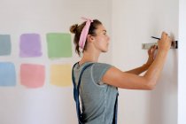 Кавказька жінка проводить вдома самоізоляцію і соціальну дистанцію в карантині під час епідемії коронавірусу 19 років, малюючи стіни свого будинку.. — стокове фото