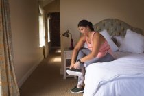 Vlogger mujer caucásica en casa en su dormitorio, preparándose para demostrar ejercicios para su blog en línea. Distanciamiento social y autoaislamiento en cuarentena. - foto de stock