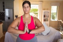 Mulher branca vlogger em casa em sua sala de estar, demonstrando exercício de ioga para seu blog online. Distanciamento social e auto-isolamento em quarentena . — Fotografia de Stock