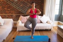 Mulher branca vlogger em casa em sua sala de estar, demonstrando exercício de ioga para seu blog online. Distanciamento social e auto-isolamento em quarentena . — Fotografia de Stock