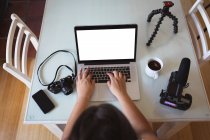 Vue aérienne d'une femme vlogger caucasienne à la maison, dans son salon à l'aide d'un ordinateur portable pour préparer son blog en ligne. Distance sociale et isolement personnel en quarantaine. — Photo de stock