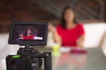 Mulher branca vlogger em casa, em sua sala de estar usando uma câmera para preparar seu blog online. Distanciamento social e auto-isolamento em quarentena . — Fotografia de Stock